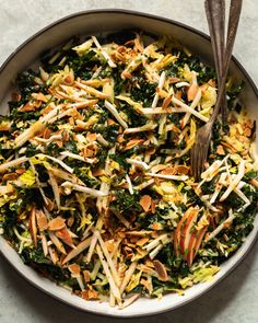 a bowl filled with shredded cheese and vegetables next to a fork on top of a table