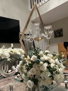 a vase filled with white flowers sitting on top of a table next to a chandelier