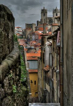 an alley way with buildings in the background and rain falling down on the roof tops