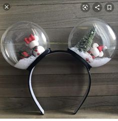 two snow globes with christmas decorations in them on top of a wooden surface,