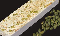 pistachios are sitting next to a white rectangular object on a black surface