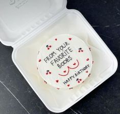 a decorated cake in a plastic container with writing on the side and hearts around it