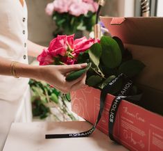 a woman is holding a bouquet of flowers in her hand and wrapping it around the box