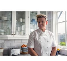 a man in a chef's outfit standing in front of a counter with oranges on it