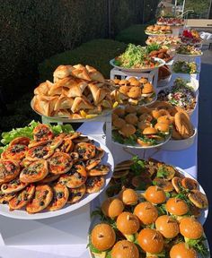 a table filled with lots of different types of sandwiches and pastries on white plates