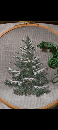 a small christmas tree is on the table next to some green yarn and scissors in front of it