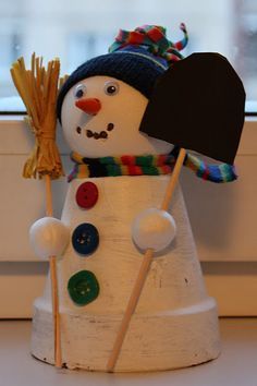 a snowman with a hat and scarf holding a broom in front of a window