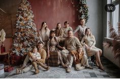 a group of people sitting next to each other in front of a christmas tree