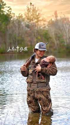 a man holding a baby in his arms while standing in the middle of a body of water