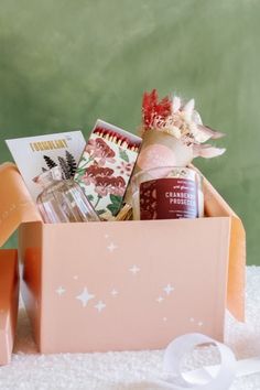 a pink box filled with lots of different items on top of a white table cloth