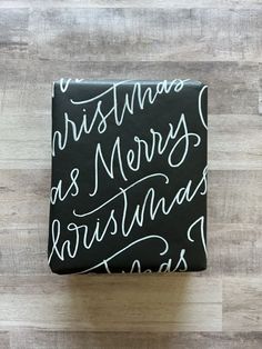 a gift wrapped in black paper decorated with white merry christmas writing Christmas Lettering Ideas, Christmas Calligraphy Cards, Bible Verse Lettering, Calligraphy Christmas Cards, Pretty Writing, Brush Pen Lettering, Christmas Calligraphy