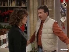 a man and woman standing next to each other in front of a book shelf filled with books