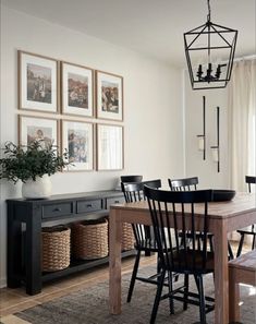 a dining room table and chairs with pictures on the wall above it, along with baskets