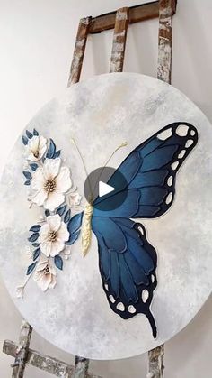 a blue butterfly with white flowers painted on it