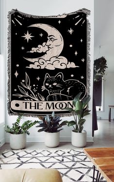 the moon tapestry hanging in a living room with plants and potted plants on the floor