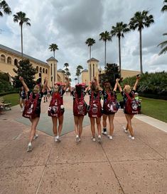 a group of cheerleaders standing in front of a large building with palm trees