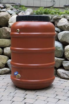 a large red tank sitting on top of a brick walkway next to rocks and plants