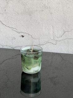 a glass filled with liquid sitting on top of a black table next to a white wall