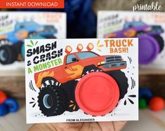 a hand holding up a card that says smash and crash a monster bash with trucks in the background