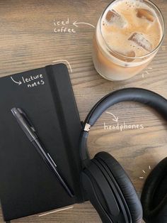 a notepad, pen and headphones sitting on a table next to a cup of coffee