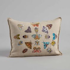 an embroidered pillow with butterflies on the front and back, sitting on a gray surface