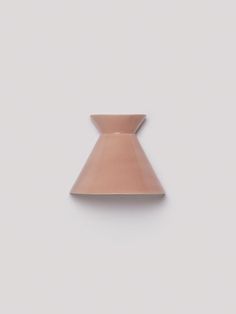 a pink vase sitting on top of a white wall