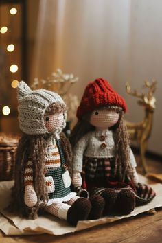 two knitted dolls sitting next to each other on top of a piece of paper