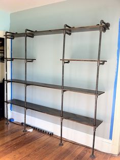 an empty room with some shelves and blue tape on the wall behind it is a wood floor