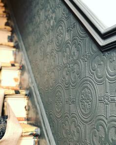 a close up view of an ornate pattern on a wall next to books and a window