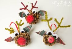 three pine cone reindeer ornaments with red noses and antlers on them, hanging from the wall