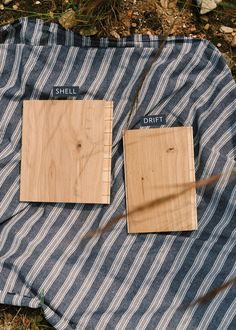 two pieces of wood sitting on top of a blue and white striped blanket next to each other