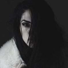 a black and white photo of a woman with long dark hair wearing a fur coat