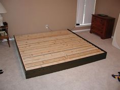 a bed frame made out of wooden boards in a room with carpeted flooring