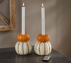 two pumpkin shaped candles sitting on top of a table