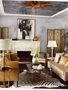 a living room filled with lots of furniture and paintings on the wall above it's fireplace