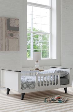 a small white bed sitting on top of a hard wood floor next to a window