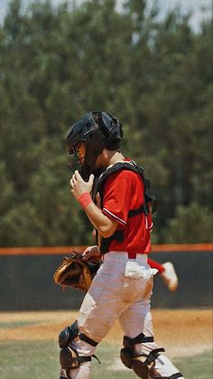 a baseball player holding a catchers mitt on top of a field with trees in the background