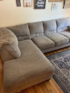 a large sectional couch sitting on top of a wooden floor next to a blue rug