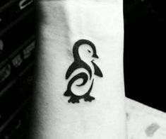 a small black and white penguin tattoo on the wrist