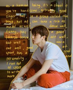 a young man sitting on top of a bed in front of a wall with writing