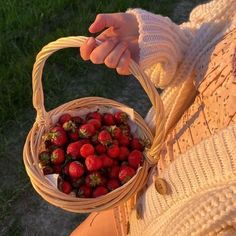 a woman holding a basket full of strawberries