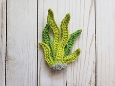 a crocheted brooch with green leaves on it