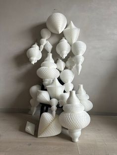 a large white sculpture sitting on top of a wooden floor next to a wall filled with vases