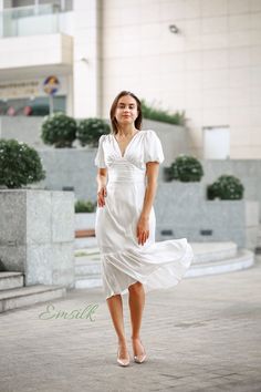 a woman in a white dress is walking down the street