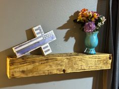 a vase with flowers on a shelf next to a wooden cross and sign that says i love you