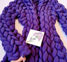 a purple knitted scarf with a flower on the end and a sticker attached to it