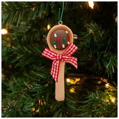 a christmas ornament hanging from a tree with a cookie on it's side