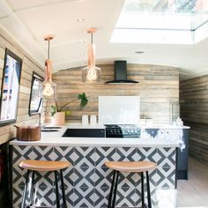 a kitchen with two stools in front of the counter and an open skylight