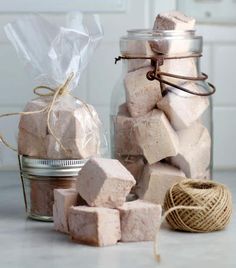 a jar filled with pink marshmallows next to a string and twine