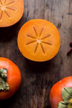 an orange cut in half sitting on top of a wooden table next to other fruit